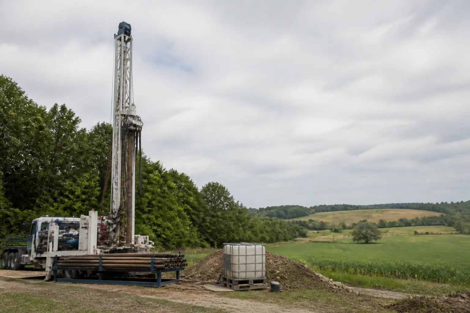Unbranded water well drilling rig set up on rural farmland